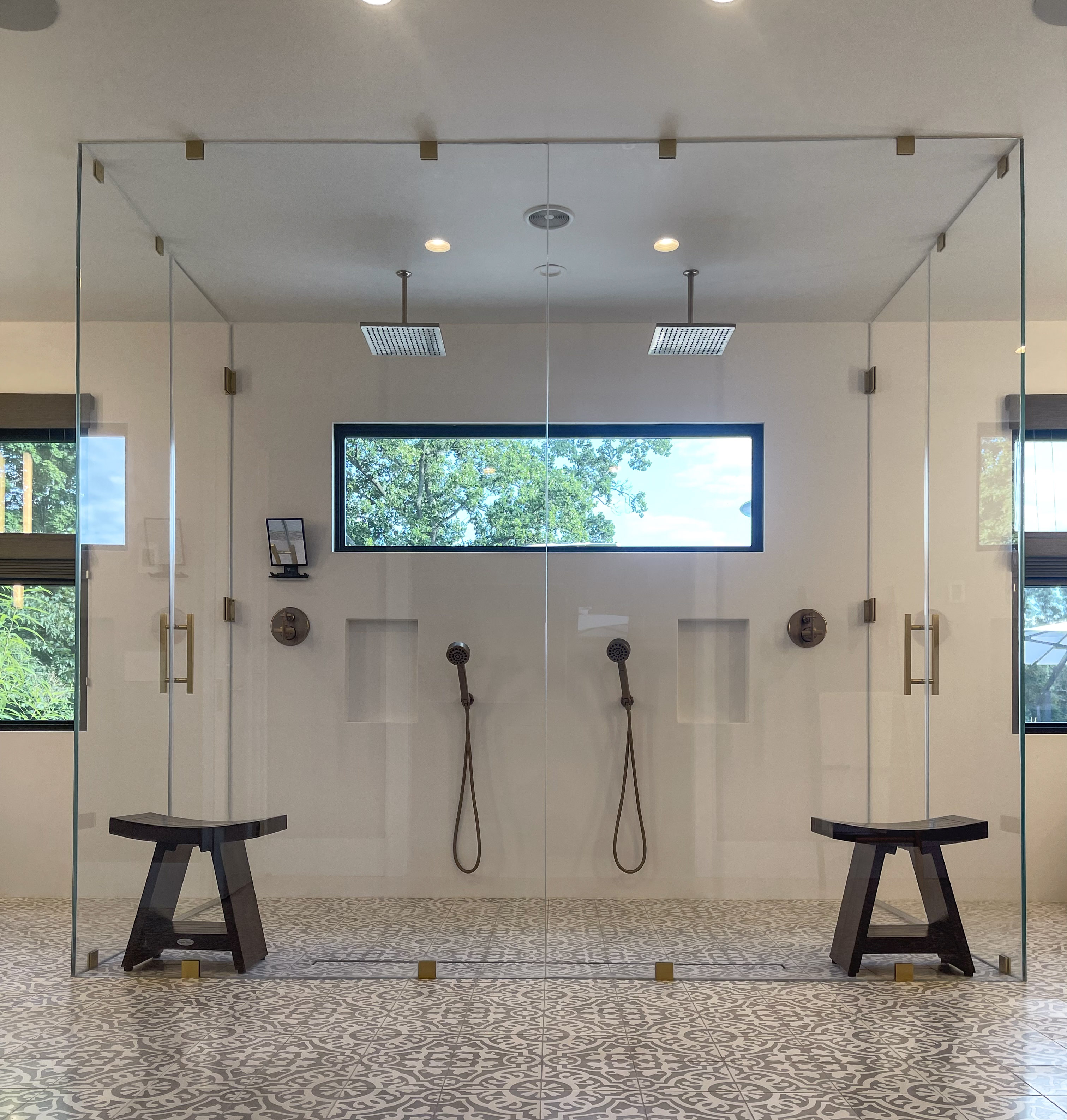 Primary bathroom with double rain shower, brass fittings, and patterned tile floor
