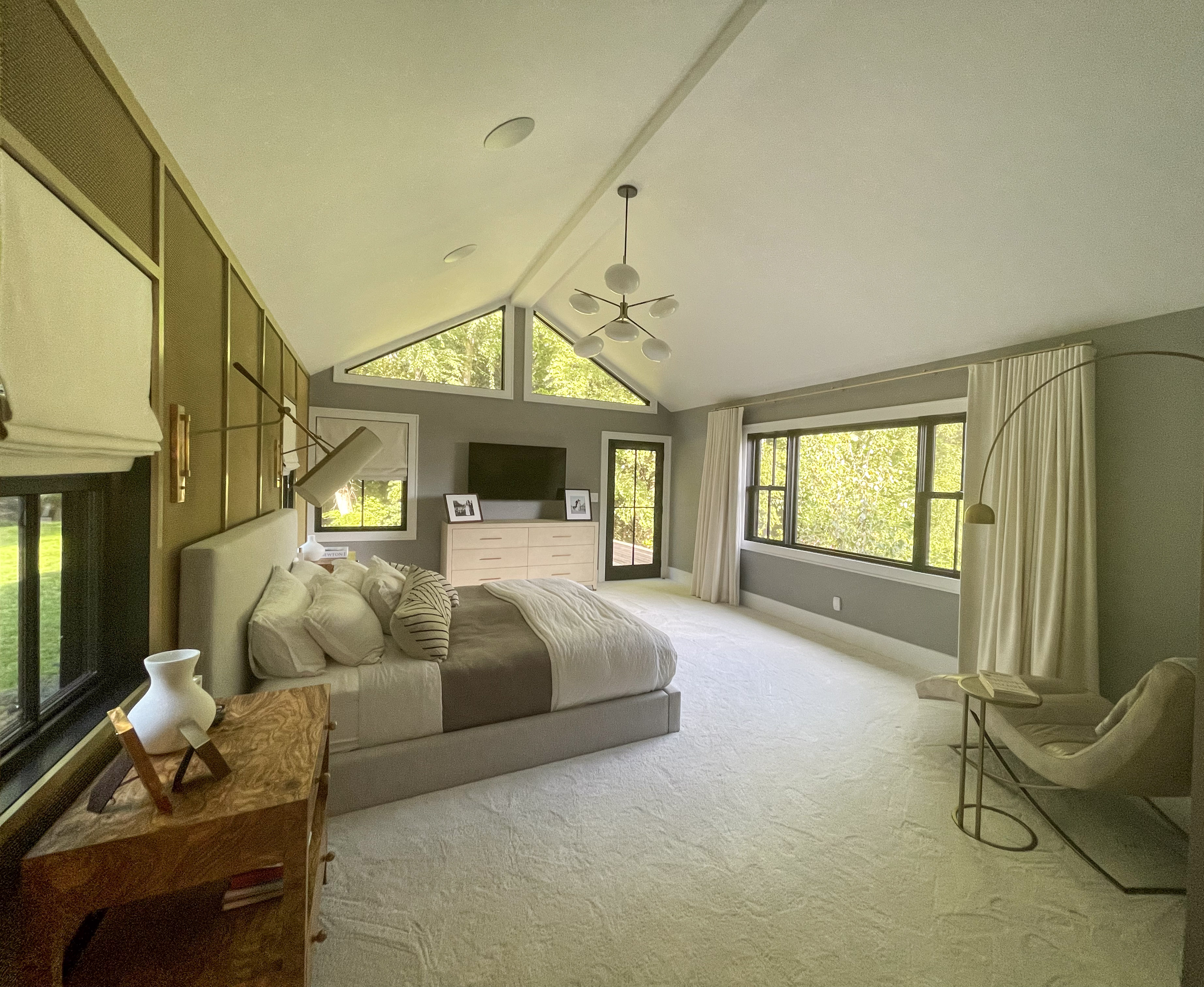 Primary bedroom with vaulted ceiling, brass sconces, and garden views