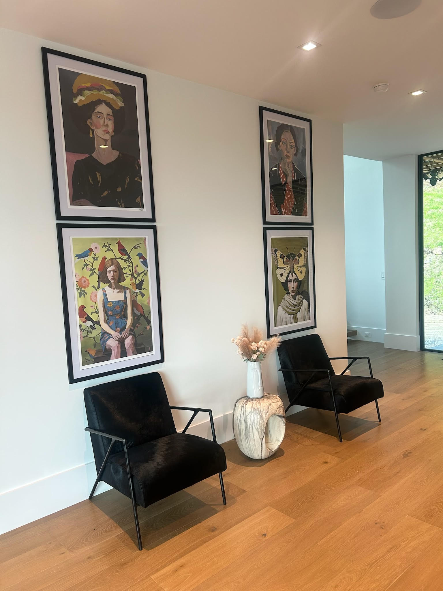 Hallway gallery wall with framed art prints and black accent chairs