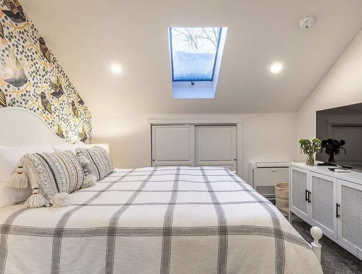 Guest bedroom with skylight and bird-print wallpaper accent wall