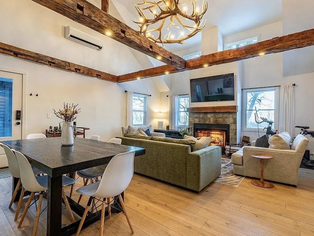Vaulted living and dining room with exposed wood beams and antler chandelier