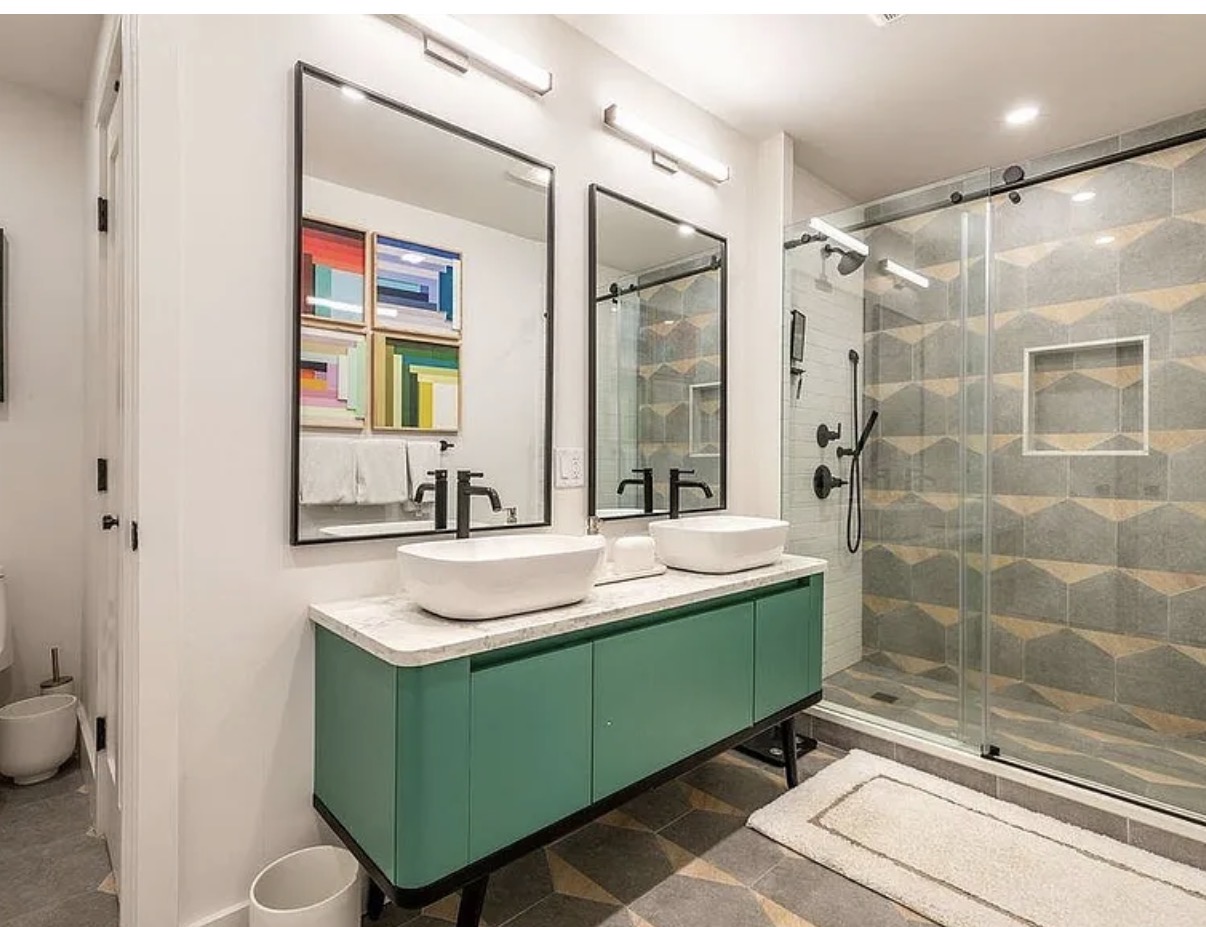 Bathroom with green double vanity and geometric tile shower