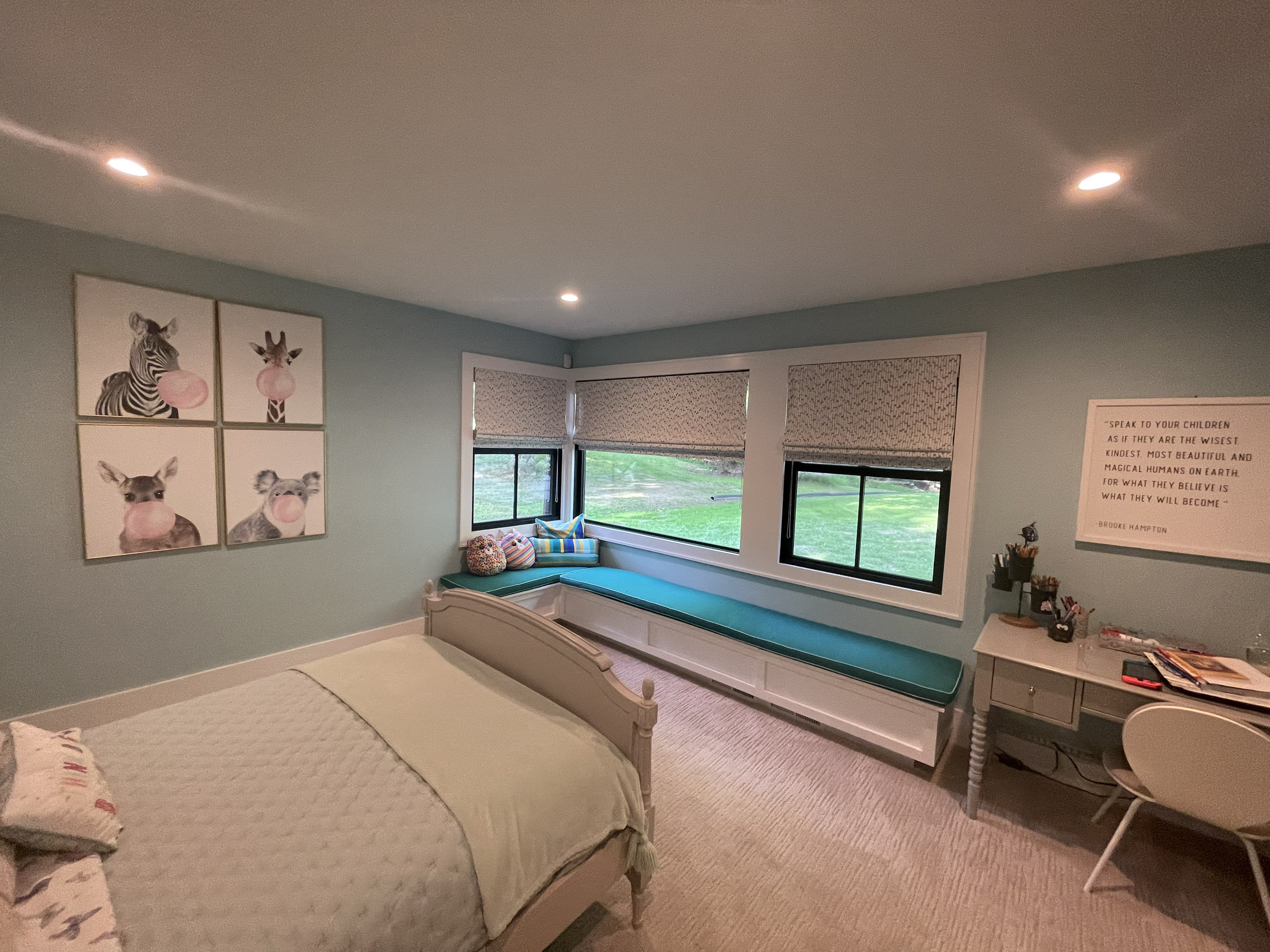 Girl's bedroom in teal with a corner window seat and animal art