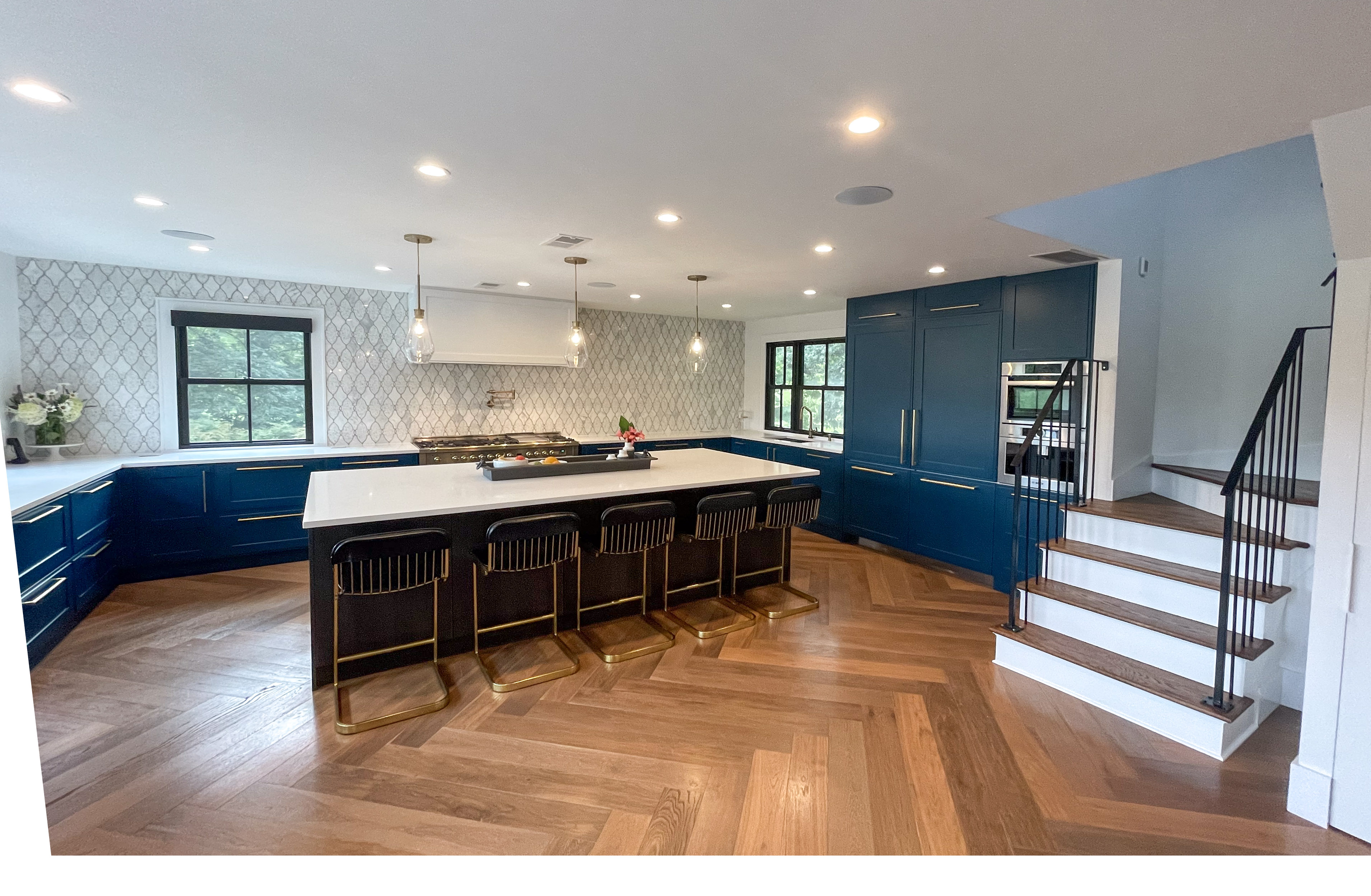 Navy kitchen island with brass barstools and herringbone floors